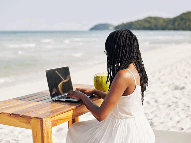 a woman works at her desk on the beach