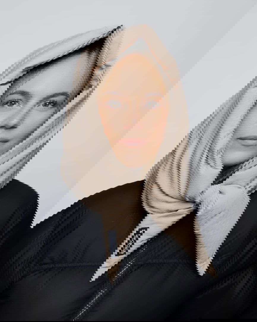 Light beige vegan winter capuche made from recycled materials, styled over black jacket. - The New Orchard CH