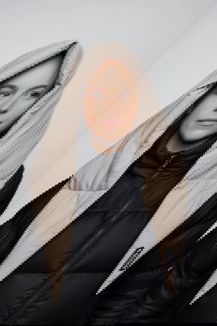 Winter Vegan Capuche Beige 2 Light beige vegan winter capuche made from recycled materials worn over a black puffer jacket. - The New Orchard CH